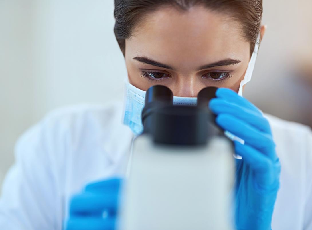 Copertina card Progetti di Rilevante Interessa Nazionale (PRIN) finanziati dal PNR. Ricercatrice con dispositivi di protezione individuale impegnata nell’osservazione di campioni al microscopio in laboratorio.